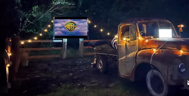 The 1953 vintage Austin Loadstar truck beside an outdoor movie screen under festoon lights