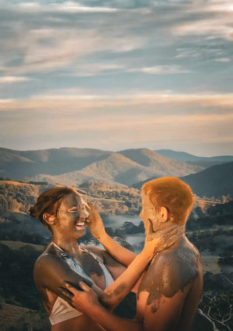 A couple covered in natural clay together at sunset during the Couples' Mud Play Experience