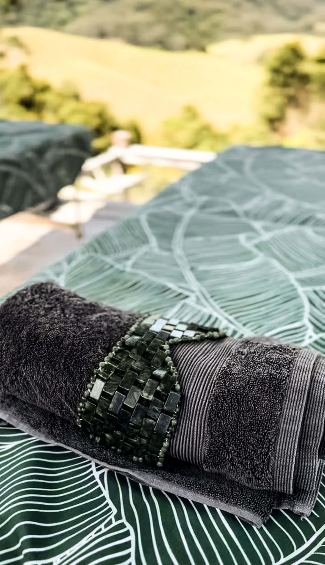 Folded towels with a bead detail resting on a lounger overlooking the paddocks