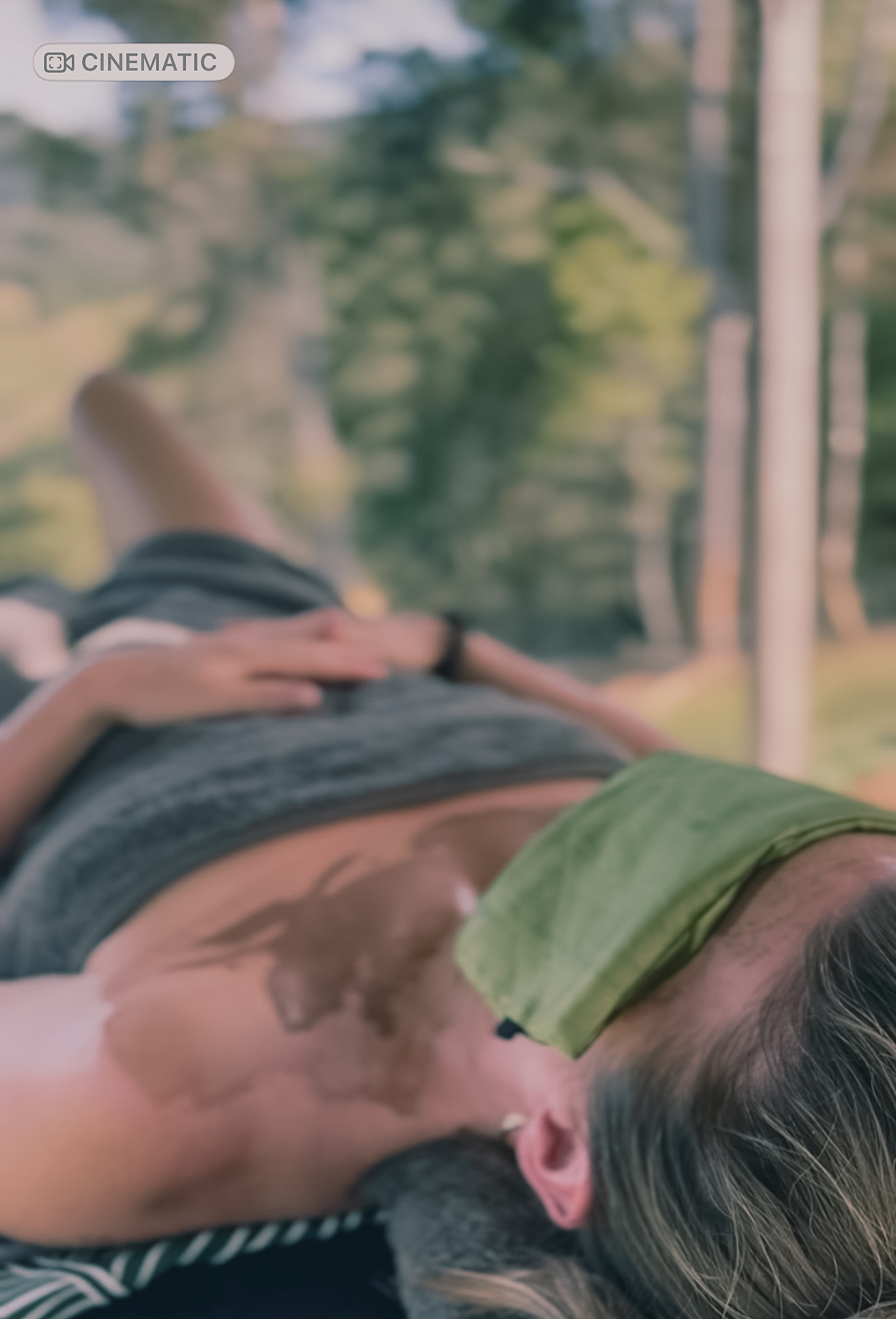 A guest relaxing outdoors with a mud mask on their chest and an eye pillow in the garden